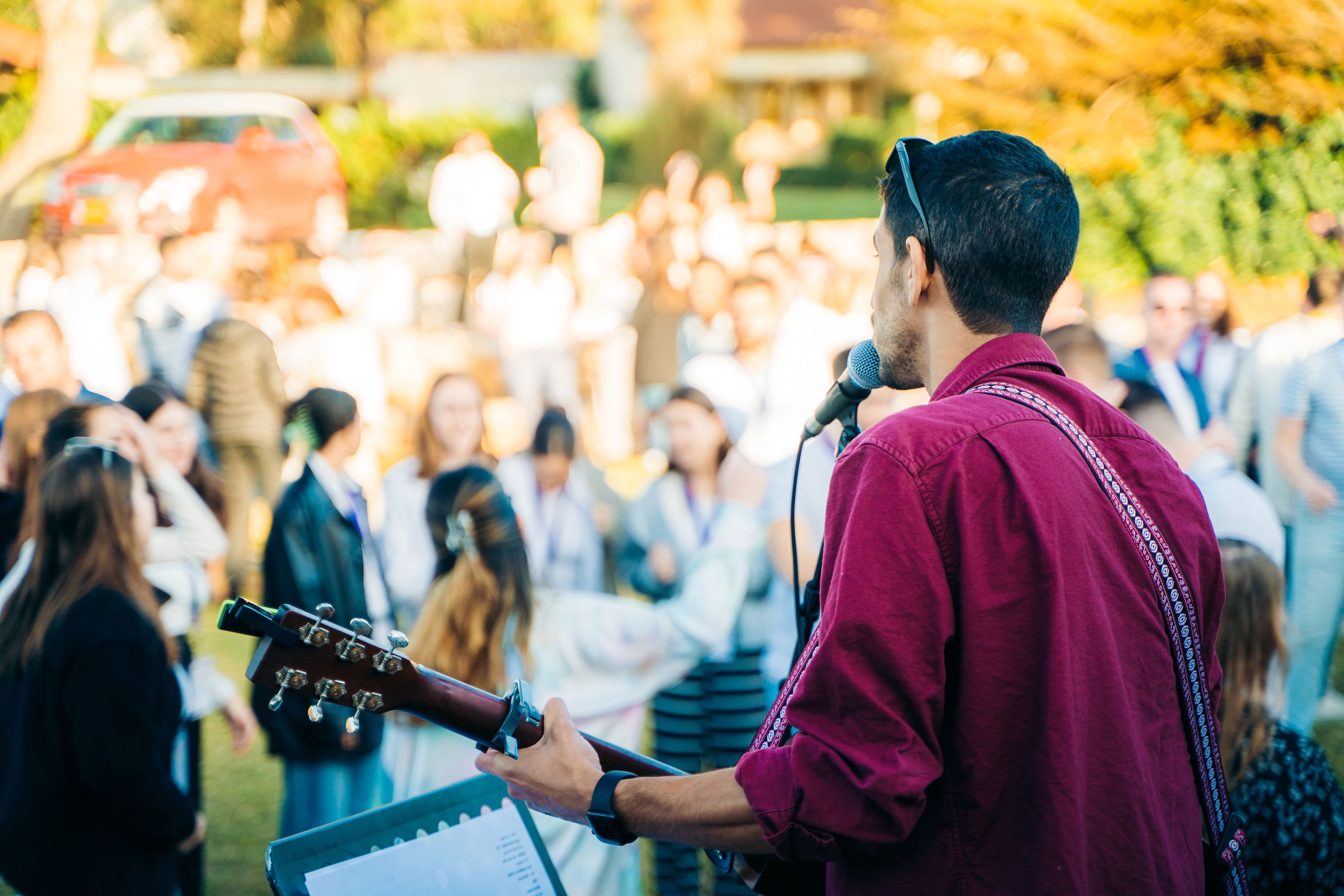 Barak leading music outdoors with people gathered